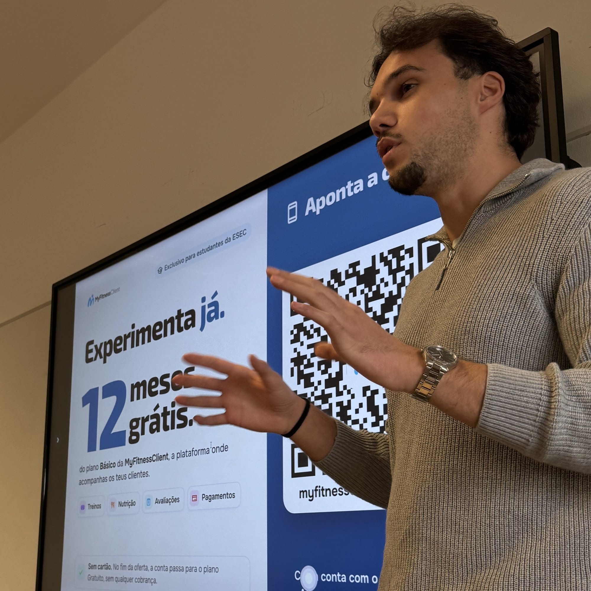 Vasco Correia, co-founder of MyFitnessClient, presenting the platform in an ESEC classroom, next to a screen with the 12-months-free offer and a QR code